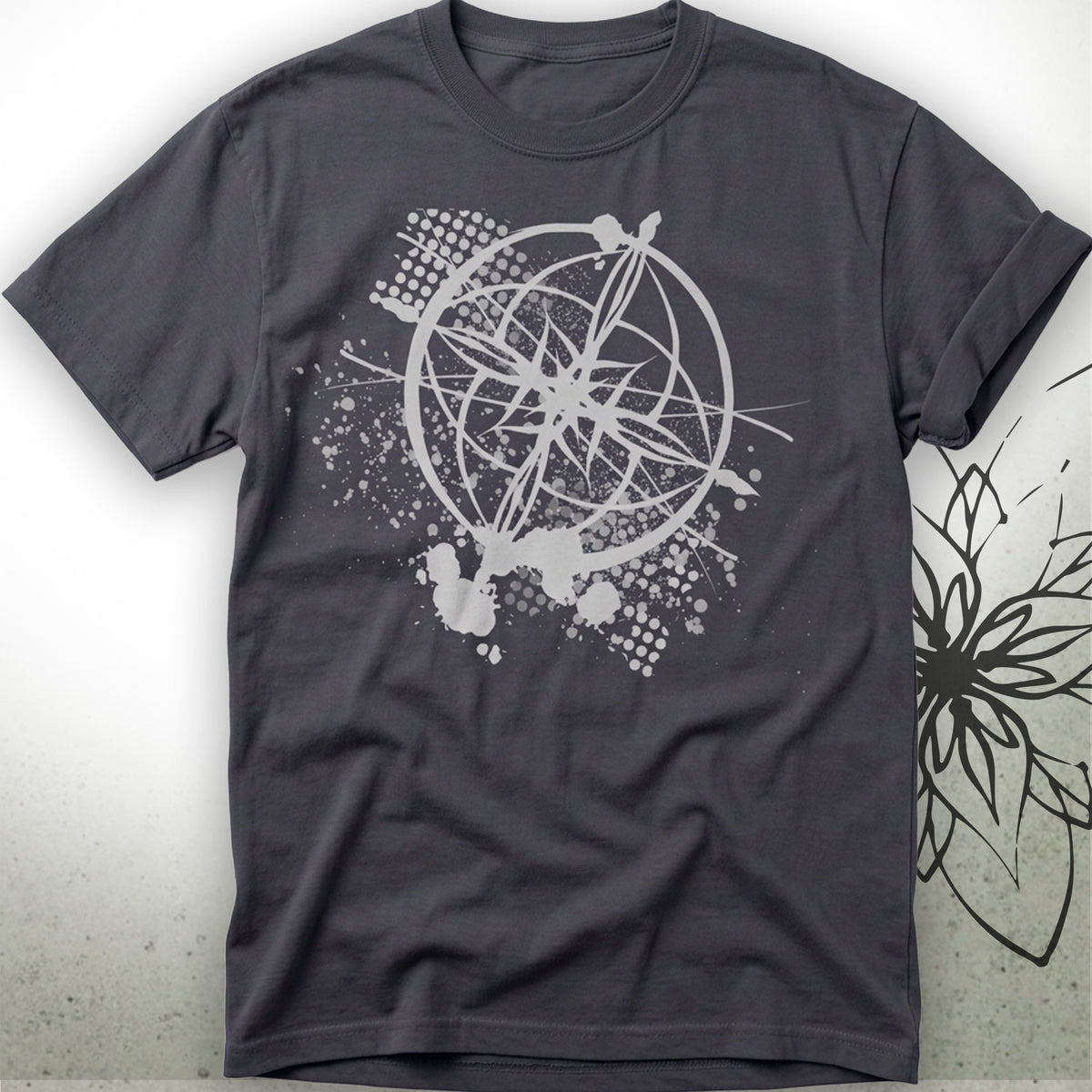 A dark charcoal gray short-sleeve t-shirt with a white graphic print of an astrolabe and geometric splatters on the front, displayed against a light gray background with a subtle floral watermark on the right.