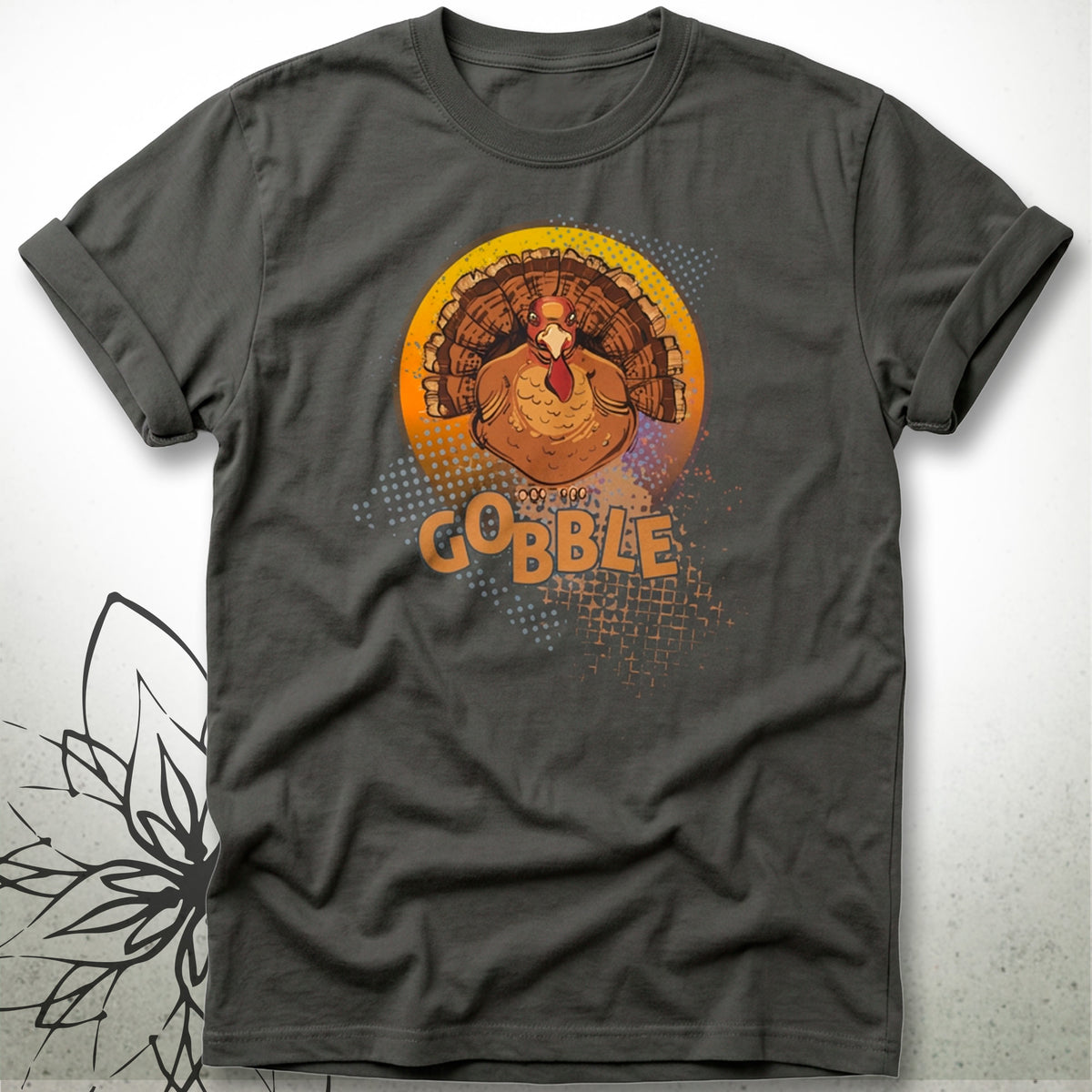 A dark charcoal gray t-shirt featuring a graphic of a cartoon turkey inside a circular orange and yellow design with the word 'GOBBLE' printed below it.