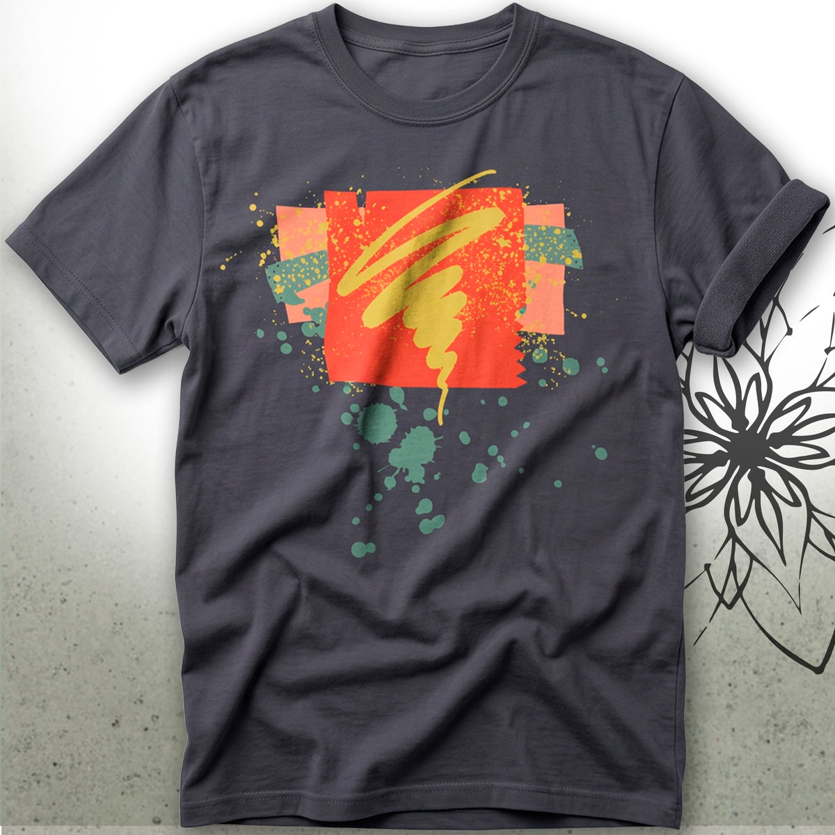 A dark gray crewneck t-shirt featuring a colorful abstract graphic print with orange, yellow, and green paint splatters and brushstrokes, displayed against a textured gray background.