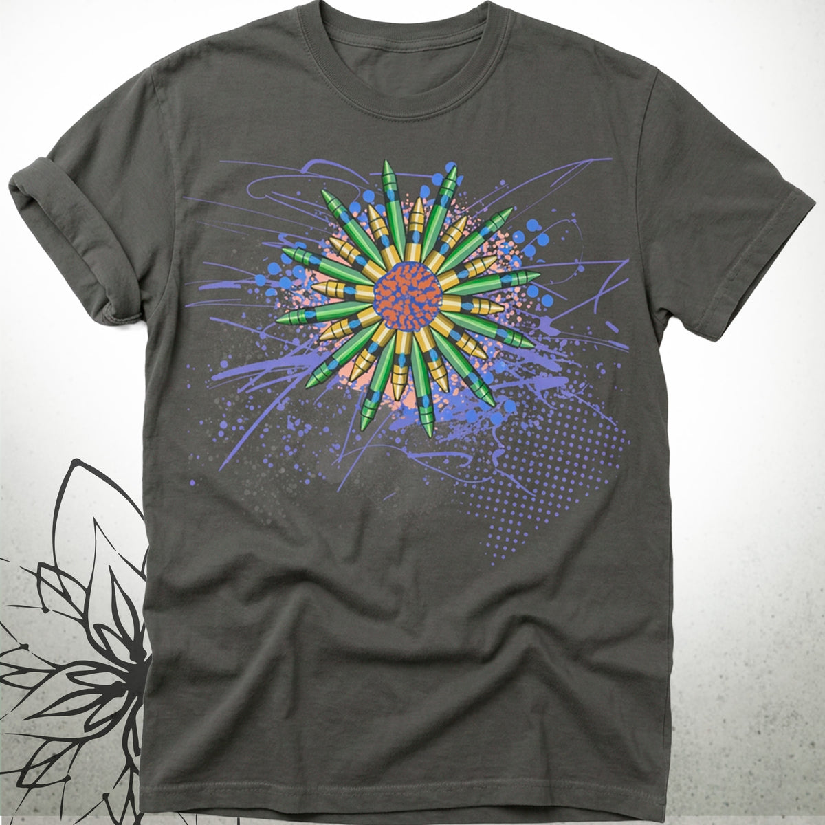 A dark charcoal gray t-shirt featuring a colorful graphic print of a stylized sun or flower made from green pencils, surrounded by blue paint splatters and dots on a light gray background.