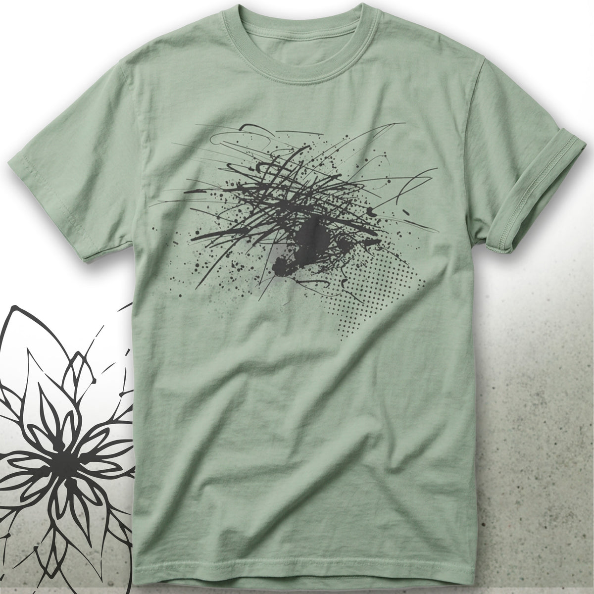 A sage green short-sleeve t-shirt with a black abstract graffiti-style graphic on the front, displayed flat against a light gray background with a black floral line-art illustration in the bottom-left corner.