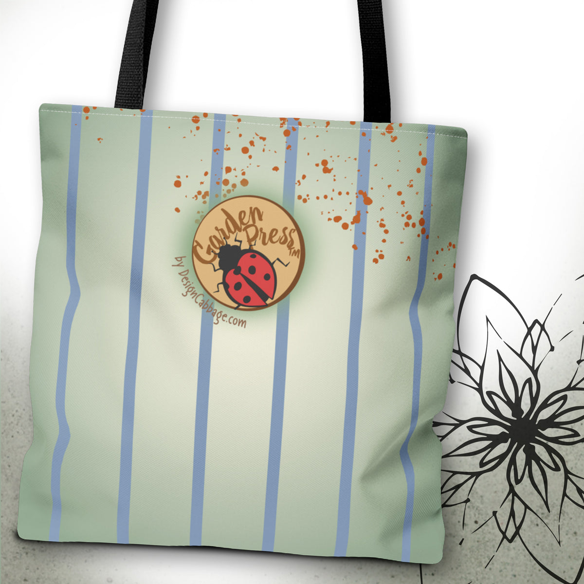 A canvas tote bag with vertical light blue stripes on a pale sage green background, decorated with orange paint splatters. It features a circular 'Garden Press' logo patch with a ladybug design and black shoulder straps, shown against a white background with a black floral sketch on the right.