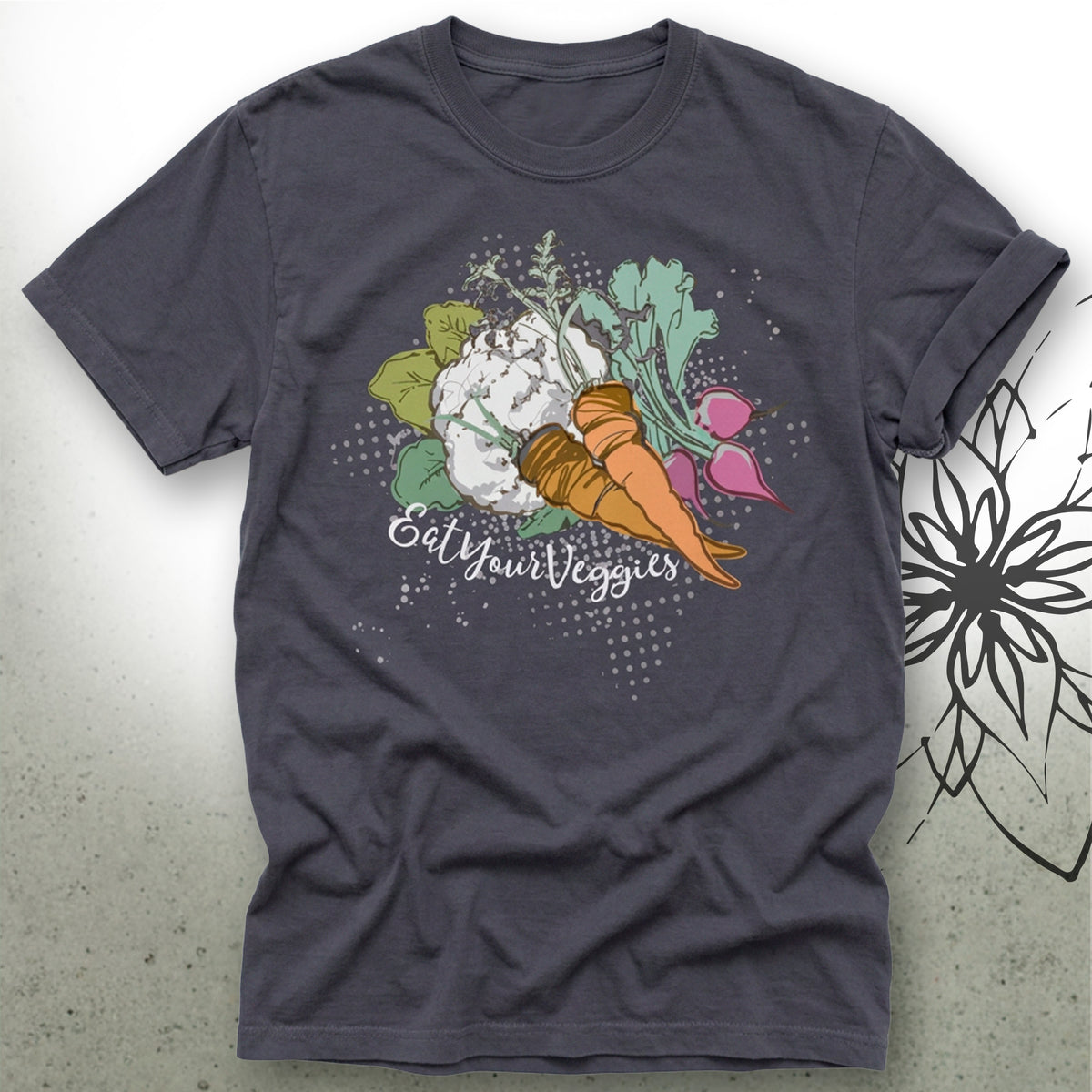 A dark charcoal gray t-shirt featuring a colorful graphic of various vegetables (carrot, radish, cabbage, spinach) with the text 'Eat Your Veggies' printed on the front, displayed flat against a light gray background.