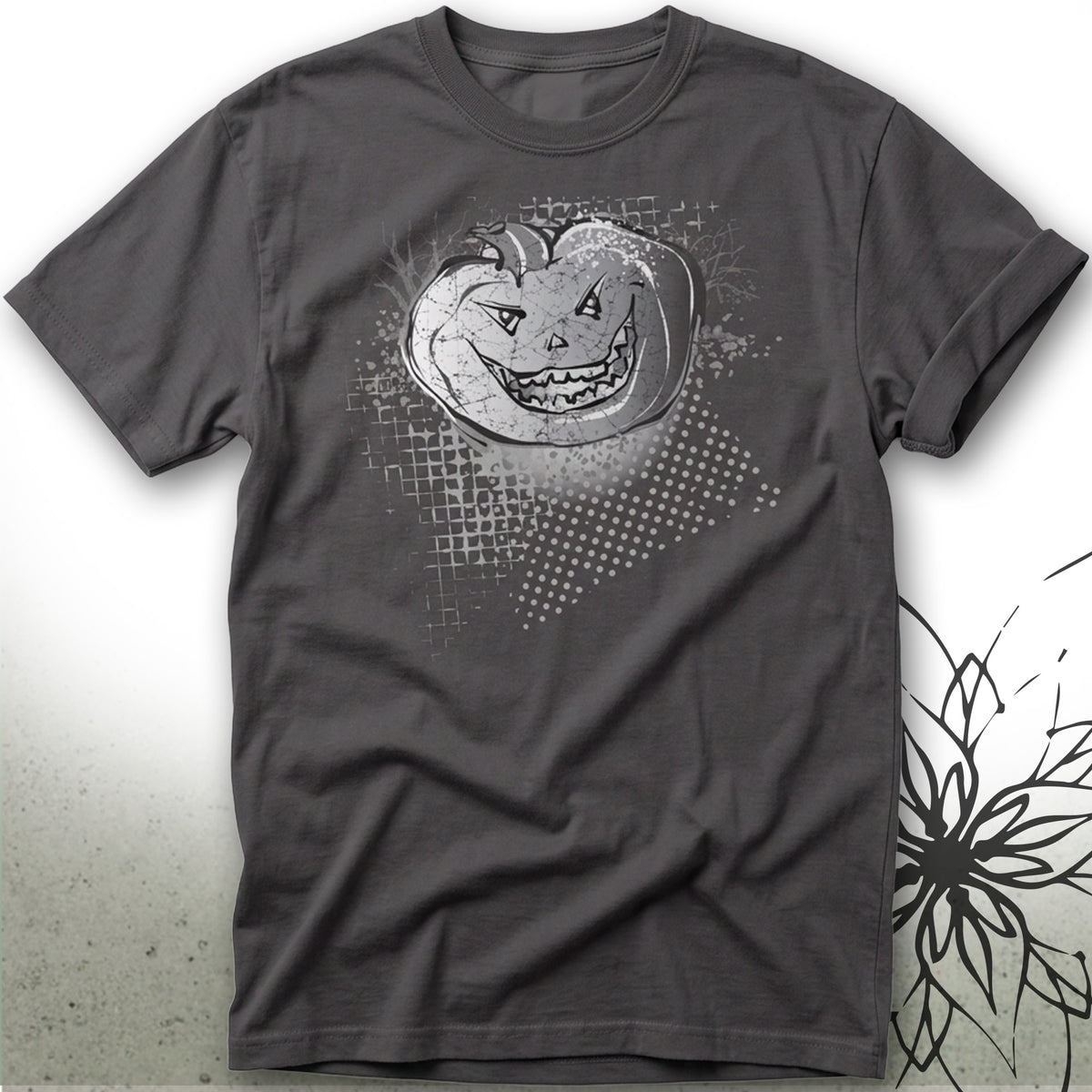 A dark gray crewneck t-shirt featuring a distressed white graphic of a jack-o'-lantern pumpkin with a glowing face, set against a light gray background with a subtle floral design on the right.